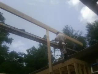 Carpenter setting a ridge beam over a new addition frame — Ice Dam Removal by Roofing Brothers in Wingate