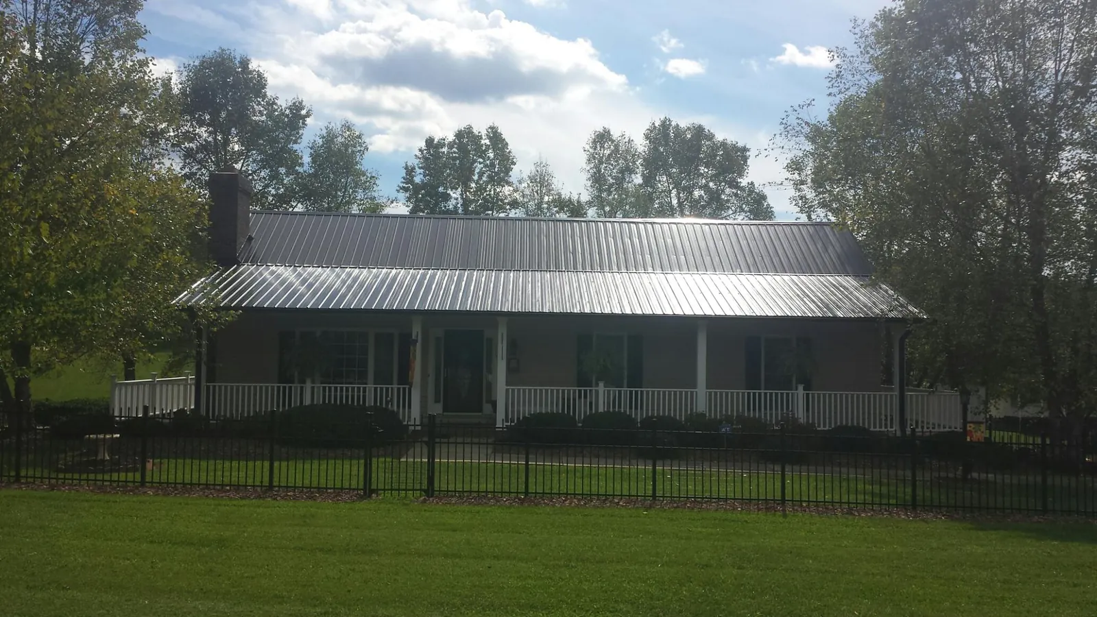 Gray metal roof on a brick ranch with a full width front porch — Gutter Guard Installation work by our crew in Wingate